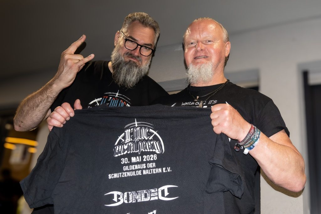 Zwei Männer halten ein T-Shirt der Gilde Metal Party Haltern
