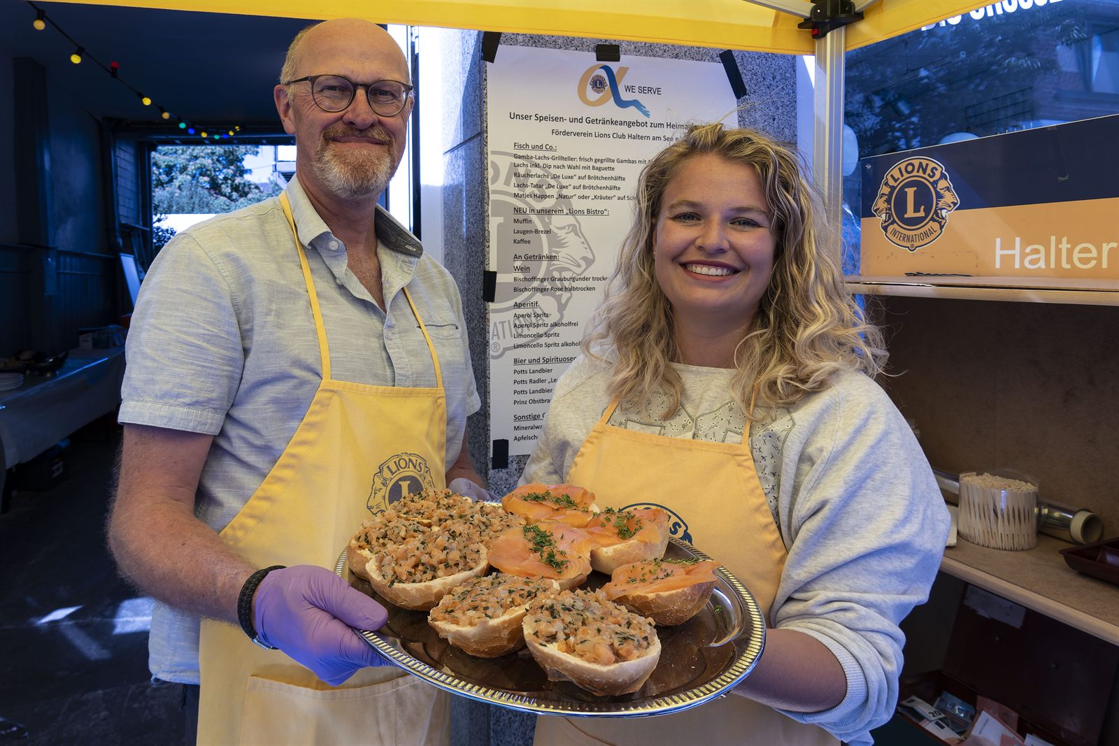 Ehrenamtliche mit Speisen an einem Vereinsstand beim Heimatfest Haltern
