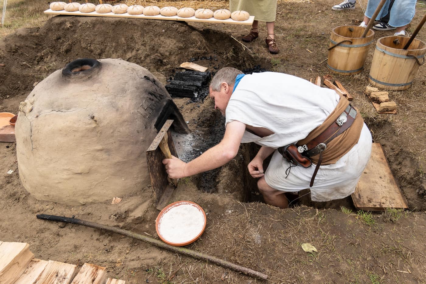 Ein Darsteller backt römisches Brot in einem Erdofen bei den Römertagen Haltern