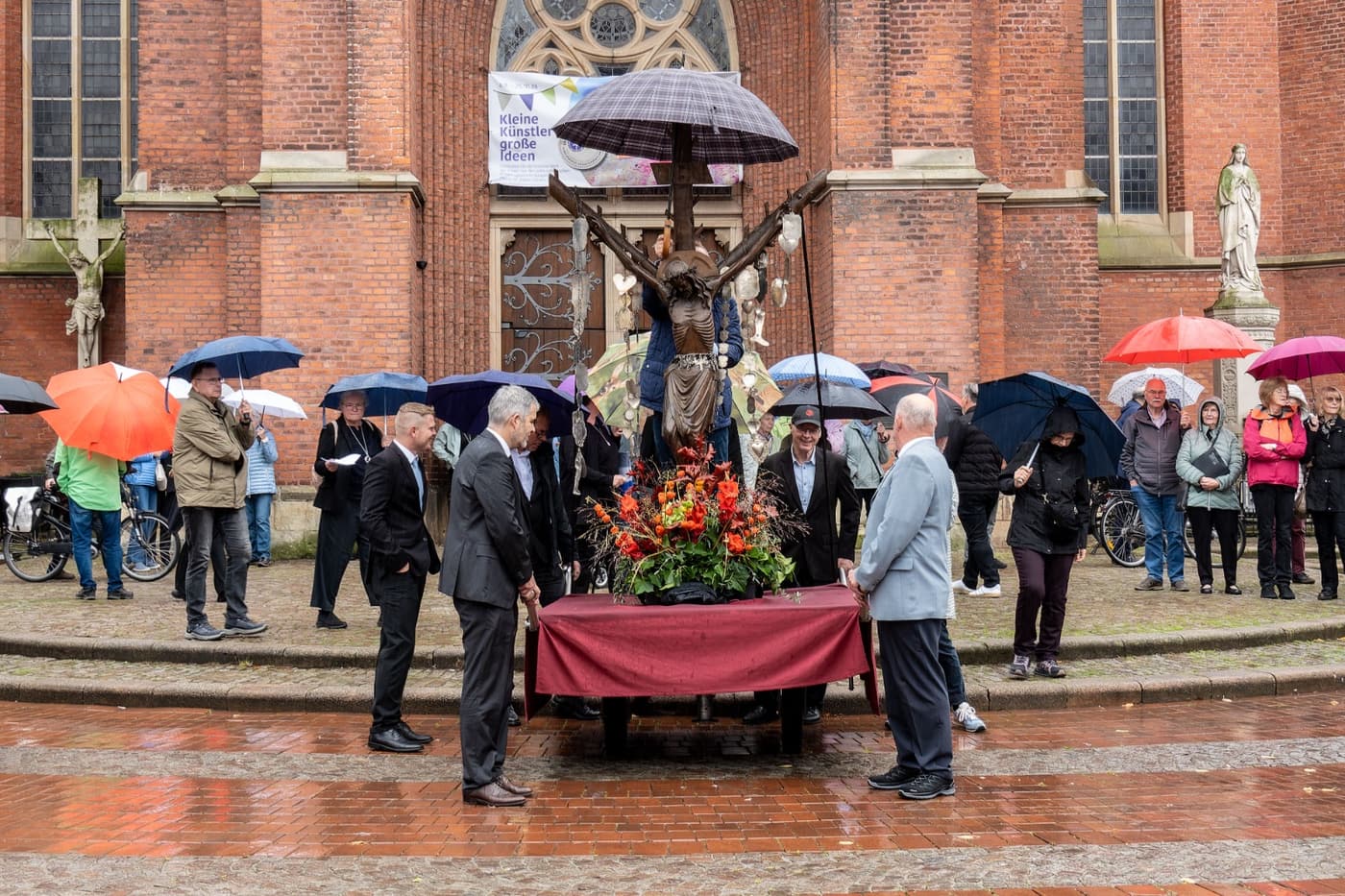 Das Halterner Kreuz wird bei der Prozession mit einem Regenschirm geschützt