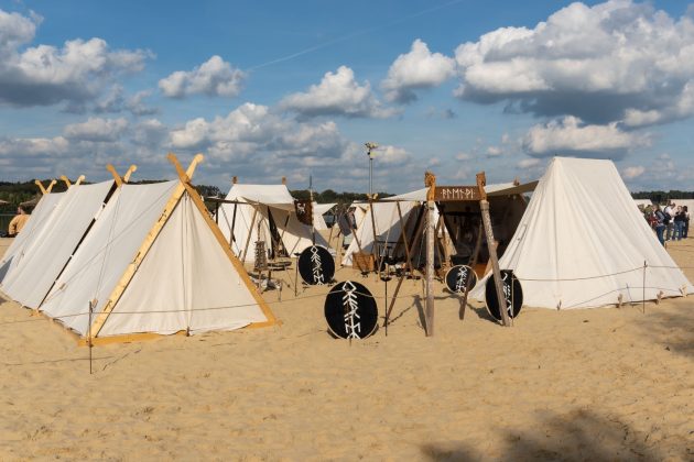 Schilde und Ausr&uuml;stung stehen zwischen den Zelten im Sand bereit