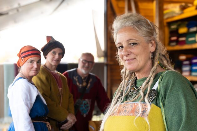 Eine Teilnehmerin in gr&uuml;n-gelber Gewandung am H&auml;ndlerstand